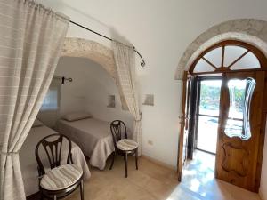 a bedroom with a bed and two chairs and a door at TRULLO FERNANDO in San Michele Salentino