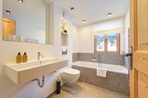 a bathroom with a sink and a toilet and a tub at Chalet SILVER FOX - Luxus Chalets in Sankt Anton am Arlberg