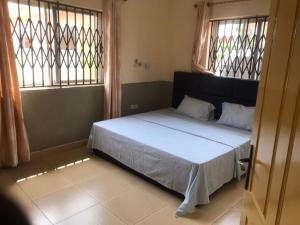 1 dormitorio con 1 cama y 2 ventanas en Devtraco courts gated community homes Tema - FiveHills homes en Tema