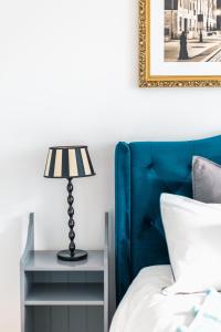 a bed with a blue headboard and a table with a lamp at Bea Home Elblag - dwie sypialnie in Elblag