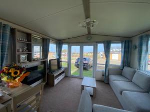 a living room with a couch and a tv at holidayhome-romneysands holiday park in Littlestone-on-Sea