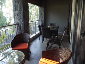 Un balcón con sillas, una mesa y una mesa con sillas. en West Terraces Residence No 5 with SEAFRONT - LICENSED BY TOURISM AUTHORITY 13516, en Flic en Flac
