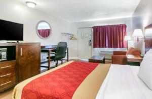 ein Hotelzimmer mit einem großen Bett und einem Schreibtisch in der Unterkunft King's Inn Motel in Reading