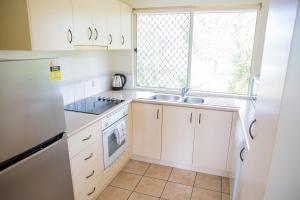 a kitchen with white cabinets and a sink and a window at 2 Bedroom Ground Level Villa in Tropical 4* Resort in Noosaville