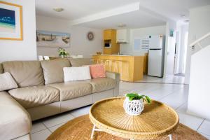uma sala de estar com um sofá e uma mesa em Tropical Getaway in 2 Bedroom Unit in 4 star Resort em Noosaville