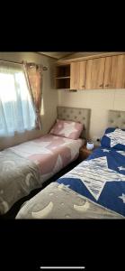 two beds in a small room with a window at Deluxe Caravan Holidays at Craig Tara in Ayr