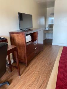 a room with a tv on top of a wooden dresser at King's Inn Motel in Reading