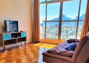 a living room with a couch and a large window at Mar, Lagoa, Vista Incrível em Ipanema in Rio de Janeiro