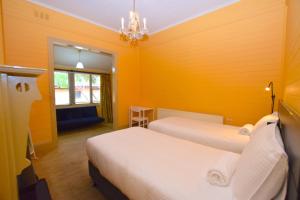 two beds in a room with yellow walls at Mary Villa in Katoomba