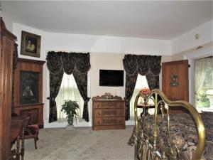 a bedroom with a bed and a tv and curtains at Raindrops On Roses Bed & Breakfast in Herkimer