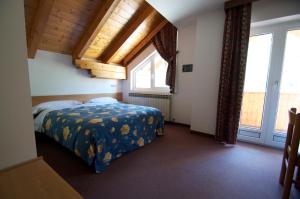 ein Schlafzimmer mit einem Bett in einem Zimmer mit Fenstern in der Unterkunft Hotel Sciatori in Passo del Tonale