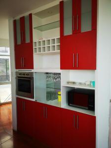 a kitchen with red cabinets and a microwave at Casa de Mateo - Zorritos - Tumbes in Zorritos