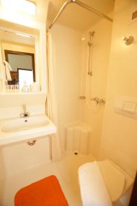 a white bathroom with a sink and a shower at Gästehaus Ethiko in Ettal