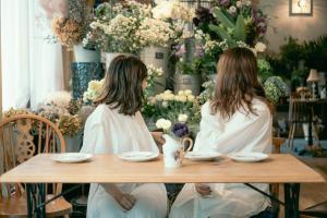 two women sitting at a table with flowers at 7 Rooms Hotel & Cafe in Tokyo