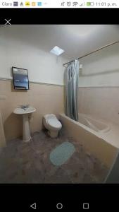 a bathroom with a sink and a toilet and a bath tub at Huellas Hostal Antigua in Antigua Guatemala