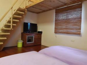 雙溪區的住宿－雙禾庭園民宿 (Shuanghu Garden B&B)，一间卧室设有一张配有电视的床和楼梯。