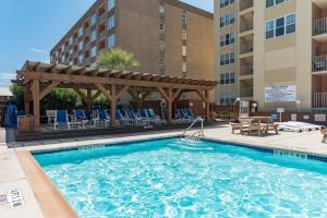a swimming pool with a pergola next to a hotel at Charming 1 Bedroom, 3 Minute Walk To The Beach Condo in South Padre Island