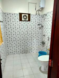 a bathroom with a toilet and a tile floor at CANALVIEW PRIVATE COTTAGE Azhikkal Ayiram Thengu in Panmana