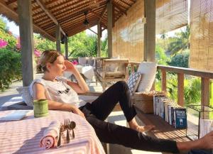Una donna seduta su un tavolo in veranda di Manusia Dunia Green Lodge a Gili Air