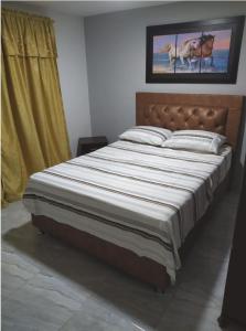 a bedroom with a large bed with a wooden headboard at Piso 2-apartment near to Cali Airport in Palmira