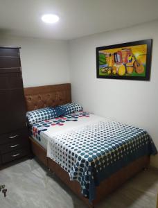 a bedroom with a bed and a painting on the wall at Piso 2-apartment near to Cali Airport in Palmira