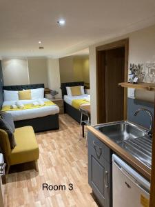 a room with two beds and a kitchen with a sink at Sutherland mini apartments in Fort William
