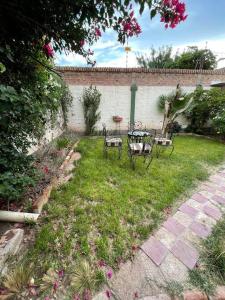 einen Garten mit zwei Bänken, einem Tisch und Stühlen in der Unterkunft Casa residencial en ubicación preferencial Dorrego in Guaymallen