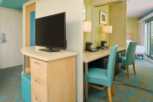 een kamer met een bureau, een televisie en stoelen bij Aston Waikiki Circle Hotel in Honolulu