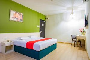een slaapkamer met een bed met een groene muur bij HOTEL 101 PERMAS JAYA in Johor Bahru