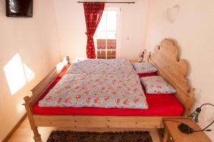 a bedroom with a wooden bed with red sheets and a window at Beim Schlenz in Reit im Winkl