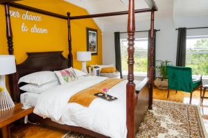a bedroom with a four poster bed and a yellow wall at The Khaya Accommodation for the Soul in Lorraine