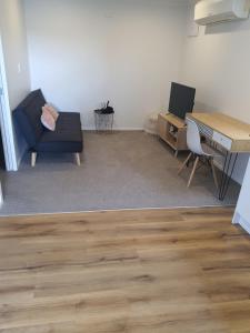 ein Wohnzimmer mit einem Tisch, einem Sofa und einem Schreibtisch in der Unterkunft Modern 1 bedroom guest house in Upper Hutt
