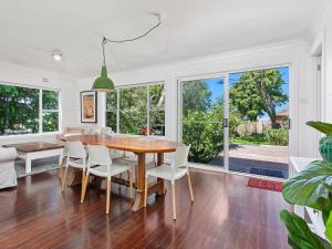 a dining room with a wooden table and white chairs at Merioola Retreat in Gerringong