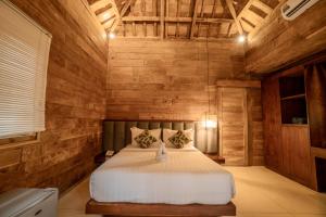 Un dormitorio con una cama grande en una pared de madera. en Rimbun Canggu Villa, en Canggu