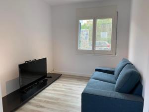 Una sala de estar con un sofá azul y un televisor. en Villa Paradise Silvia, en Sant Pere de Ribes