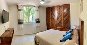 a bedroom with a bed and a television and a window at El Colorín, a condo in the heart of Huatulco in Santa Cruz Huatulco