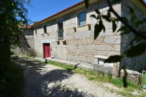 a brick building with a red door on the side at Casa da Choqueira in Vieira do Minho