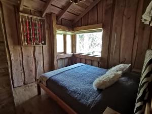 a bedroom with a bed in a wooden cabin at Wonderful rustic cabin 2, with native logs, on the banks of the Trancura River in Pucón