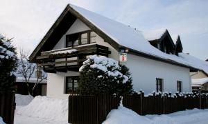 une maison recouverte de neige avec une clôture dans l'établissement Penzion Familia Antol, à Liptovský Mikuláš
