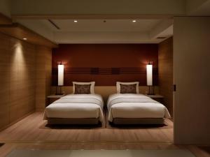 a bedroom with two beds and two lights on the wall at Kobe Minato Onsen Ren in Kobe