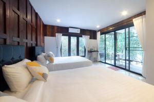 a bedroom with two beds and a large window at Tawan Riverside in Mae Wang