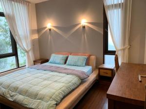 ein Schlafzimmer mit einem Bett mit zwei Kissen und zwei Fenstern in der Unterkunft CA Homestay Borneo Highland in Kampong Teng
