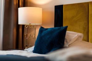 a bed with a blue pillow and a lamp at Prawdzic Family Resort & Wellness in Gdańsk