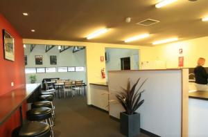a restaurant with a bar with stools and a table at Swansea Backpackers in Swansea