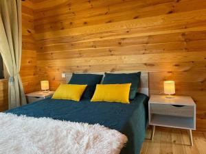 1 dormitorio con 1 cama con 2 almohadas amarillas en Le Chalet du Crescent, en Saint-Germain-des-Champs