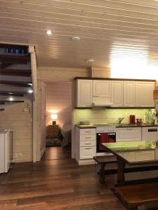 uma cozinha com armários brancos e uma mesa em Aada Villa by the slopes em Syöte