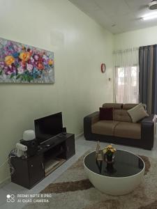 Una sala de estar con un sofá y un televisor. en Taiping Desa Jana Home Stay, en Kamunting