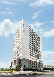 a tall white building with a blue sign on it at Risen Ocean Park Hotel in Sokcho