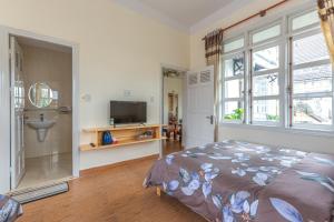 a bedroom with a bed and a tv and a window at MENTO Villa Đà Lạt in Da Lat