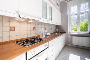 uma cozinha com armários brancos e um forno com placa de fogão em Victus Apartamenty, Apartament Grand em Sopot